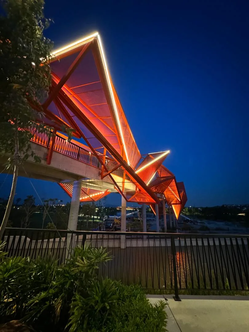 Orange lattice canopy bridge lit at dusk at Elmina Lakeside Mall